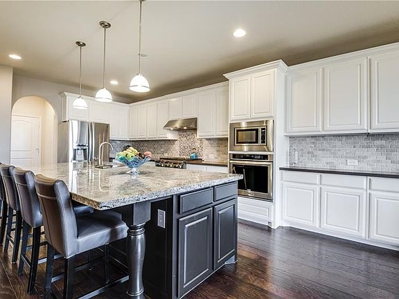 You will be amazed at this highly upgraded kitchen! Oversized island with granite and pedestal legs, complimented with gray silestone counters along wall with high end tile backsplash & elegant pendant lighting!
