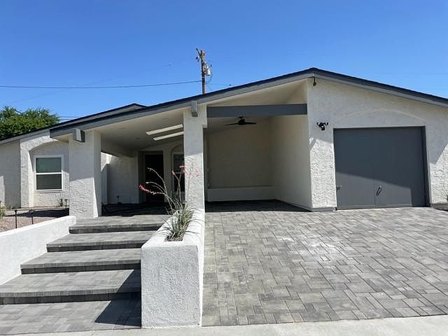 Dramatic entry with wide low rise steps, Pavered 2 car driveway with covered carport that can be used as a covered front porch in addition to the sprawling backyard.