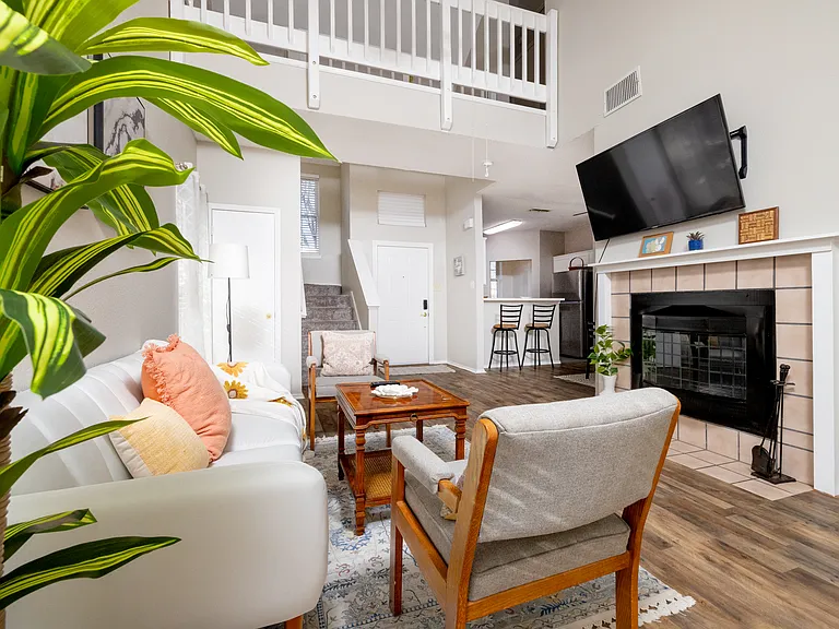 Cozy, spacious living room featuring a comfy couch, two chairs, a warm fireplace, TV, and a bookshelf stocked with books and games_perfect for relaxing or entertaining.