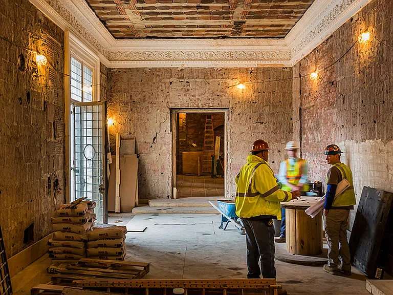 During Renovation: Skilled construction team discussing plans in a room with exposed brick