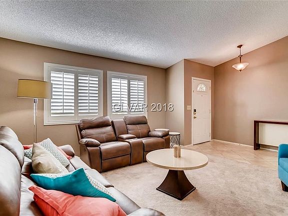 Cozy living room with vaulted ceilings and plantation shutters welcome you.