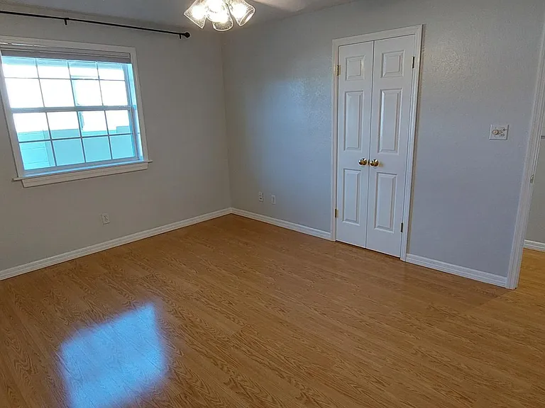 Primary bedroom and doors to full bath and hallway. Window looks out on a courtyard.