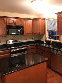 Kitchen with mobile island Cherry cabinets and dishwasher.