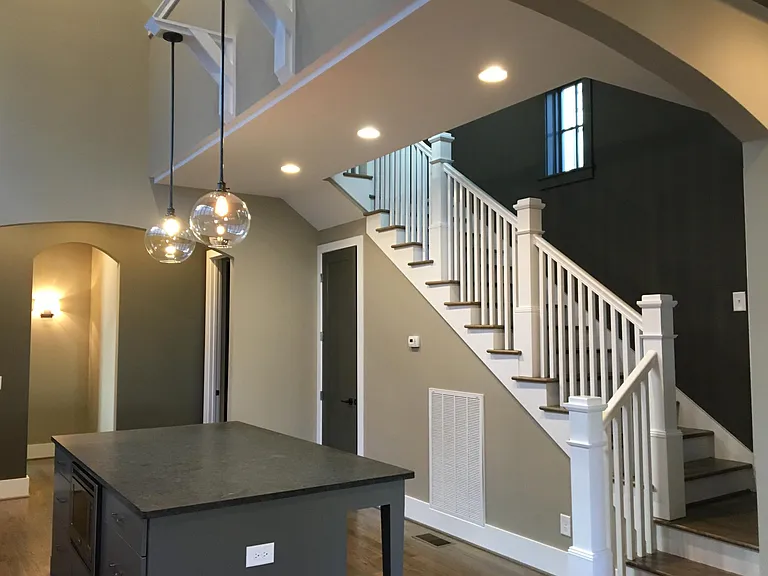 View from living room into kitchen and up the stairs. This also shows the doors to the large walk-in pantry and powder room.