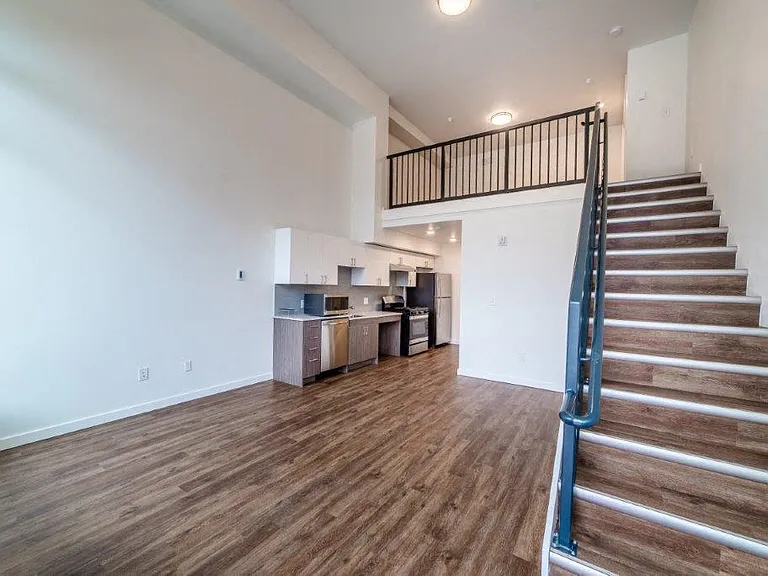 An open concept layout in Lillehammer Apartments featuring hardwood floors and a staircase.