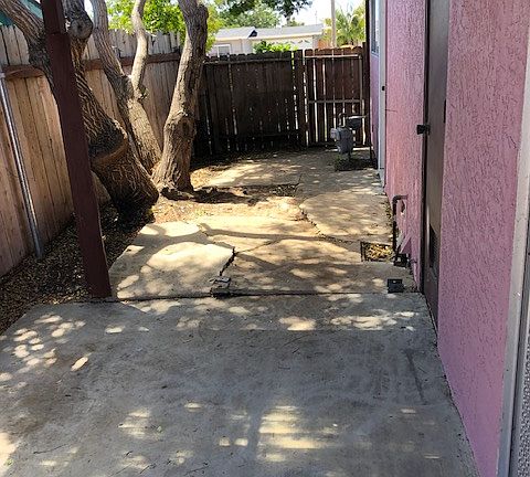 Side covered patio with slab and gate to front yard and back door to garage.