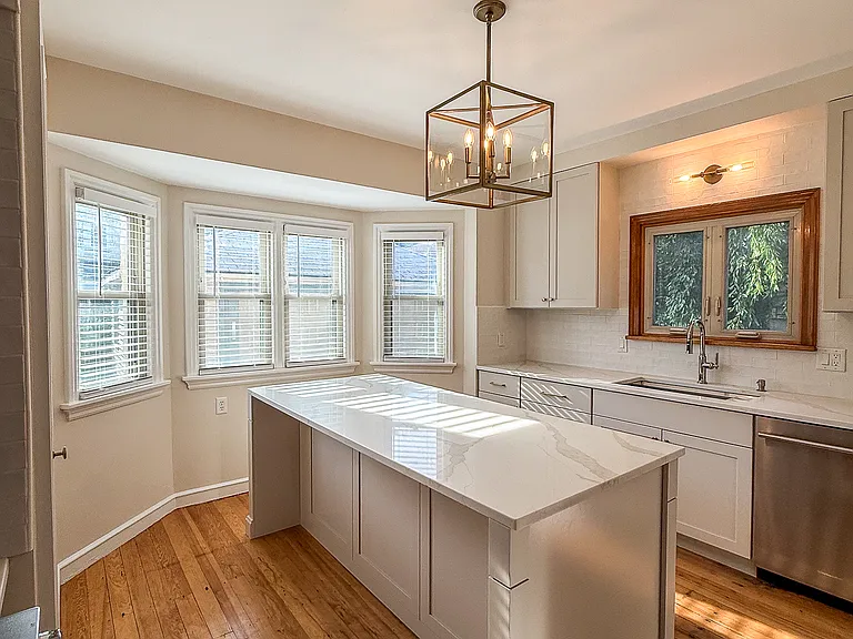 Fully renovated kitchen featuring brand new cabinetry, Kitchen Aid appliances, quartz counter and island for seating and meal prep.