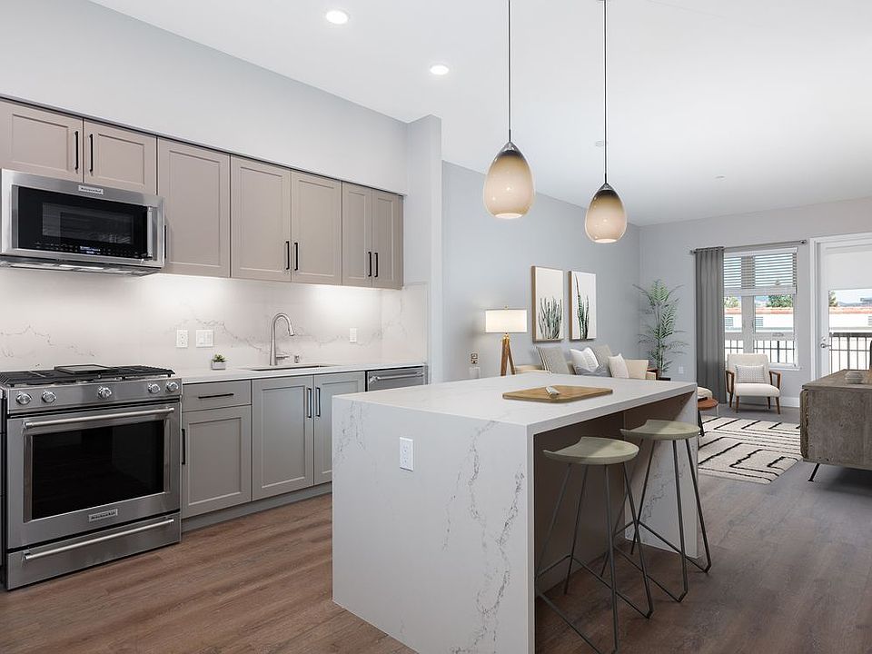 Phase II Signature Collection Kitchen and dining area with grey cabinetry, white marble countertops and backsplash, upgraded stainless steel appliances, and hard surface flooring