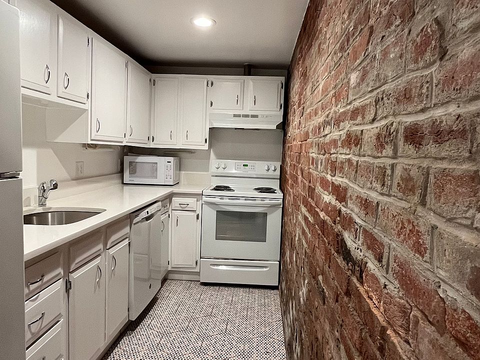 Full kitchen with dishwasher and exposed brick wall