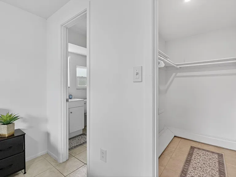 Dedicated walk-in closet with hanging rods and shelf storage and in-suite bathroom