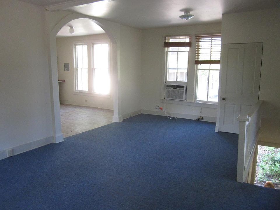 Living/sleeping room carpeted, archway into kitchen