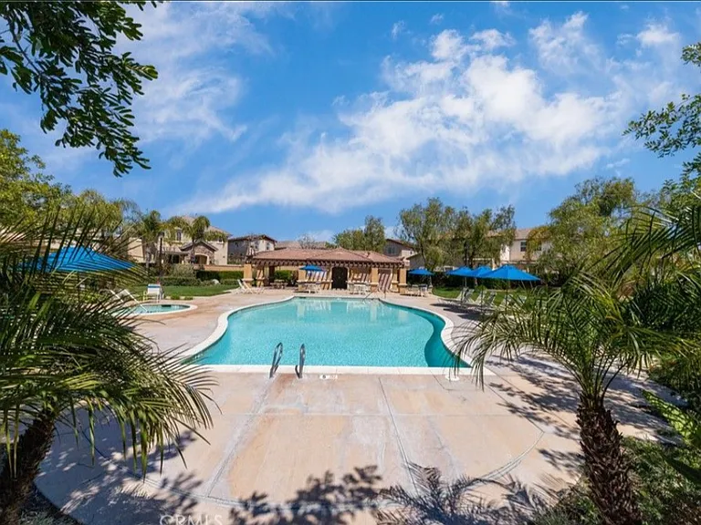 This picture shows the refreshing community pool and spa, with bathrooms and shade.