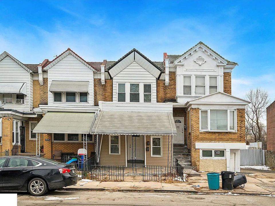 Brick-front duplex with a covered porch and gated front entry. Situated on a quiet residential block with street parking available. A small outdoor space at the front offers added convenience and versatility.