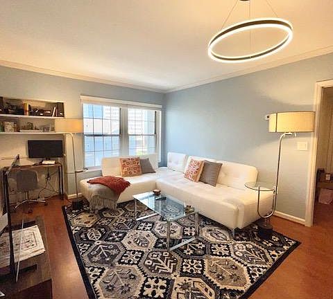 Spacious living room with white leather sofa, new matching carpet and runner, big windows, and unique lighting fixtures.