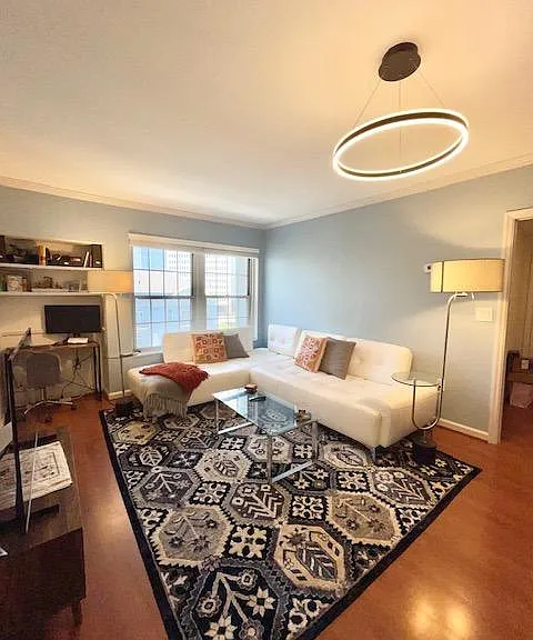 Spacious living room with white leather sofa, new matching carpet and runner, big windows, and unique lighting fixtures.