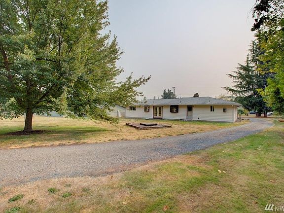 Back of home with view of the long driveway from 66th Ave E, level lot for vehicles. Boat storage, room for RV/manufactured home with water, power and 2BD septic system installed.  