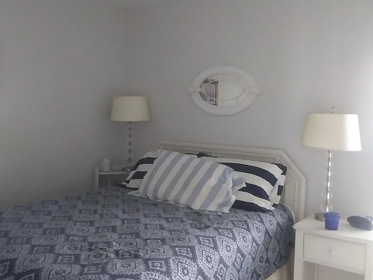 Another view of the bed with the lamps and nightstand.