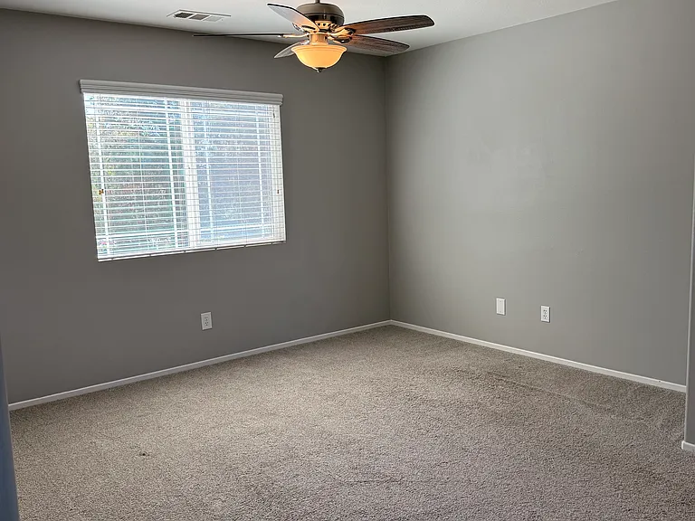 Upstairs loft/office with ceiling fan and big window.