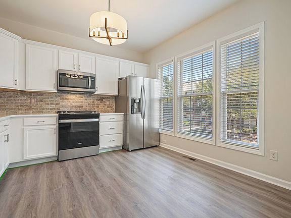Kitchen View with LVP, Quartz Countertops, and Tumbled Travertine Backsplash