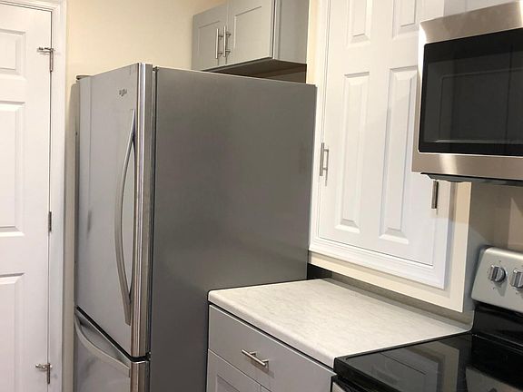 Kitchen area with stove, refrigerator, microwave, and cabinets.