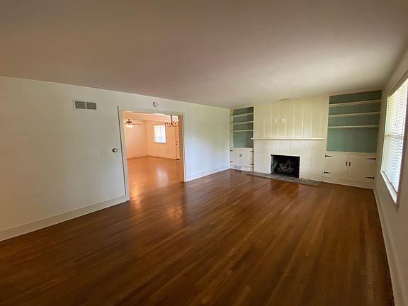 Living room with gas-log fireplace and book shelves, looking into dining room and family room.