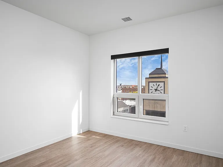 Bright and airy bedroom with a large window featuring a charming city view and iconic clock tower. Bright and airy bedroom with a large window featuring a charming city view and iconic clock tower.