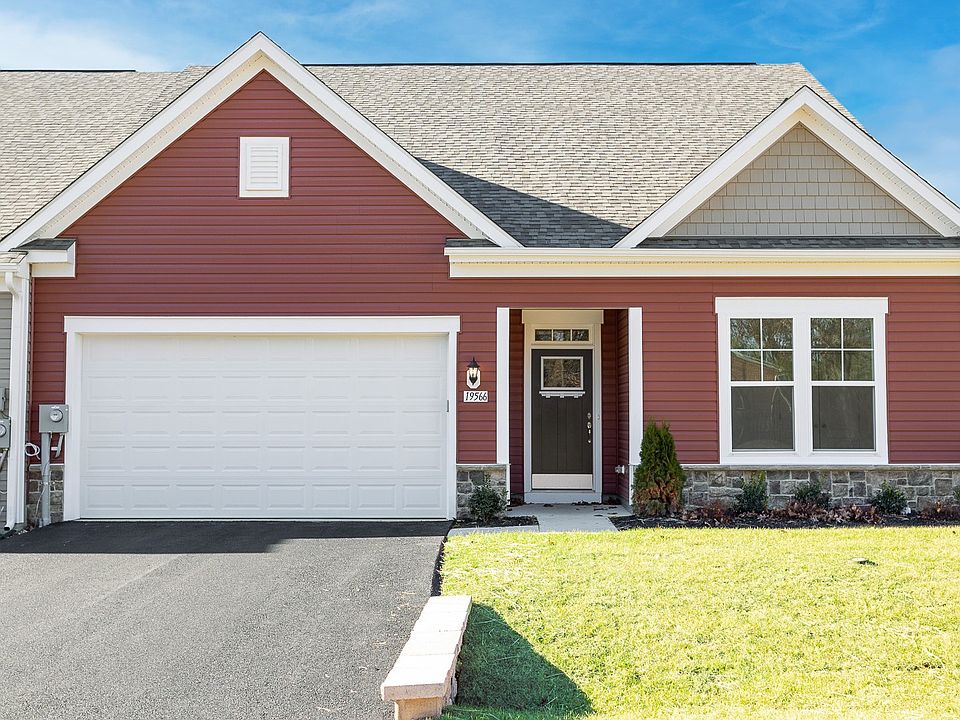 Front of home with 2 car garage, covered entry and red exterior of a DRB Homes Finch home in the Ros
