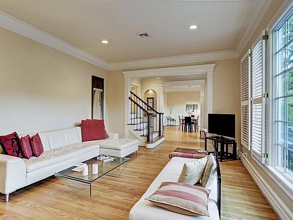 Another view of the lovely living room showcasing the gorgeous hardwood flooring throughout and open floor plan. Exceptional crown moldings and door entry mill work can be seen here as well.