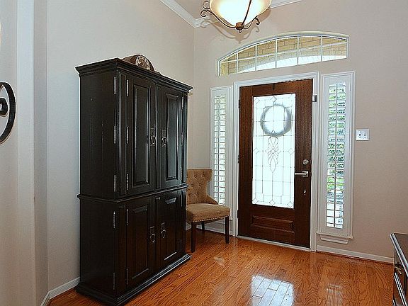 The leaded glass door opens to wood flooring a high ceiling with crown molding and a lovely light fi