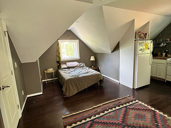 Light filled studio with sloped ceiling over the bed. Note this apartment is unfurnished. View from window above bed is to the South.