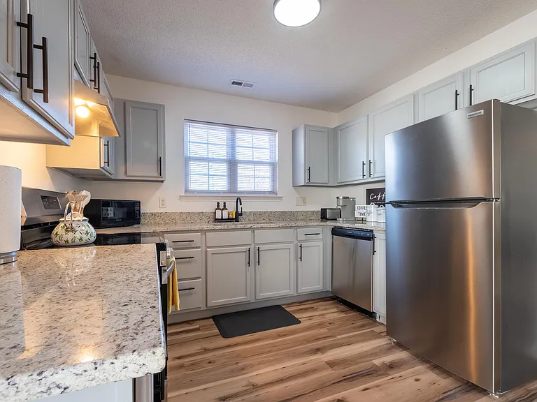 Updated kitchen with stainless steel appliances, generous cabinet storage, and expansive granite-look counters for meal prep.
