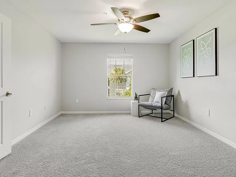 Indulge in serene bedroom luxury featuring expansive windows, plush carpeting, and a ceiling fan for peaceful nights.