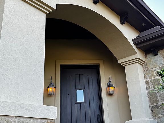 Stucco columns, iron lanterns, and solid stone bases add Old-World charm to the main entry.