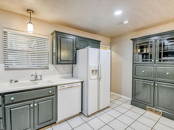 Kitchen with subway tile backsplash, new cabinets, Corian countertops, and newer appliances