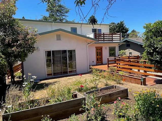 Rear view from backyard and deck and upstairs balcony