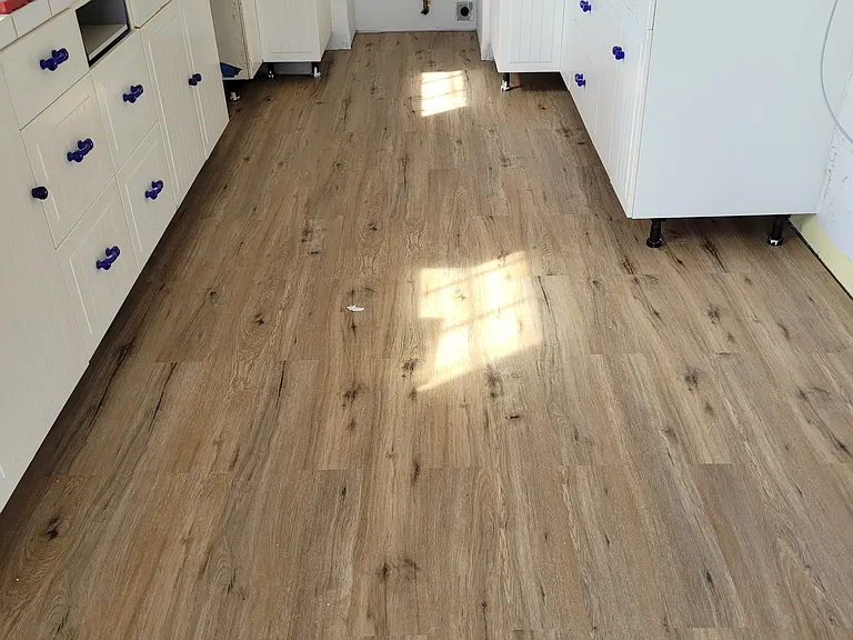 Kitchen during the new floor install. Kitchen is equipped with range, over the range microwave, dishwasher and refrigerator.