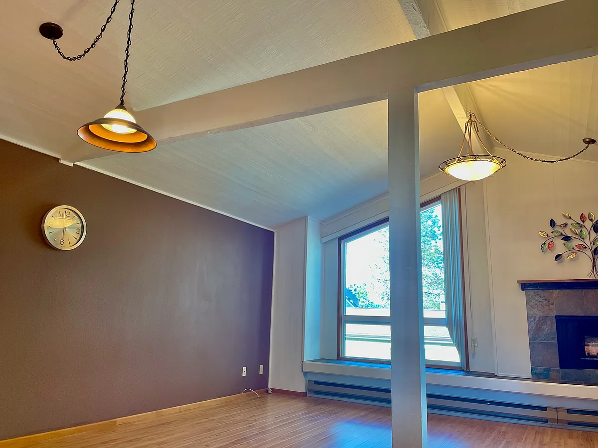 Open living room and dining room with wooden decorative beams and hanging chandeliers. - 7579 Old Redmond Rd #6