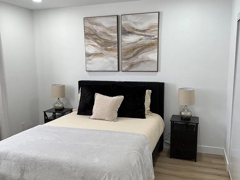 Furnished bedroom featuring a full bed, matching nightstands with lamps, and durable wood-look flooring for easy upkeep.
