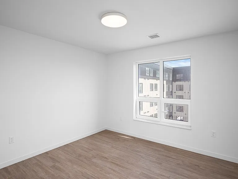 Bright, sunlit room with modern light fixture, large window, and stylish wood flooring, perfect for a cozy bedroom or office space. Bright, sunlit room with modern light fixture, large window, and stylish wood flooring, perfect for a cozy bedroom or offic