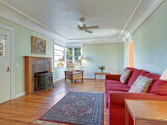 Looking east across the living room with hardwood floors, cove celings, archway to formal dining room, Vermont Castings wood stove, oak hardwood floors and excellent natural light.