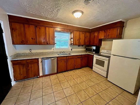 Kitchen equipped with appliances, dishwasher, refrigerator and stove. Granite counter tops.