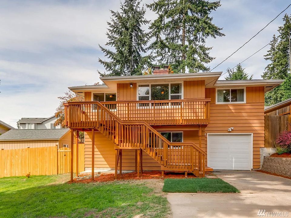 Front of home, has a entry door at lower steps and also another entry door just to the left behind the fence.