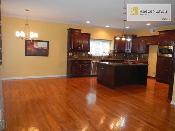 Large ioen kitchen wtih gleaming wood floors, granite island wit