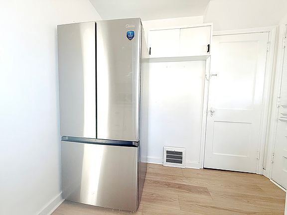 First floor _ newly renovated kitchen with brand-new French-door refrigerator, 4-burner stove, microwave and modern countertops, offering a clean and functional cooking space.