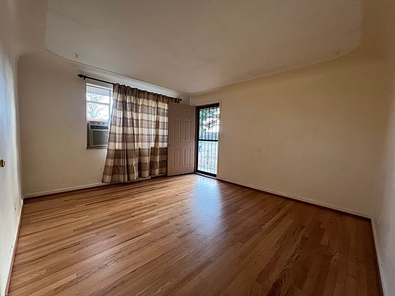 Living room, fresh paint and newly refinished hardwood floors. Window air conditioner. Front door.