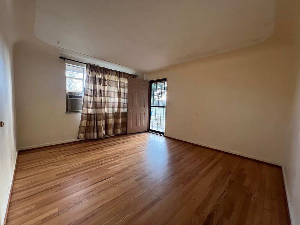 Living room, fresh paint and newly refinished hardwood floors. Window air conditioner. Front door.