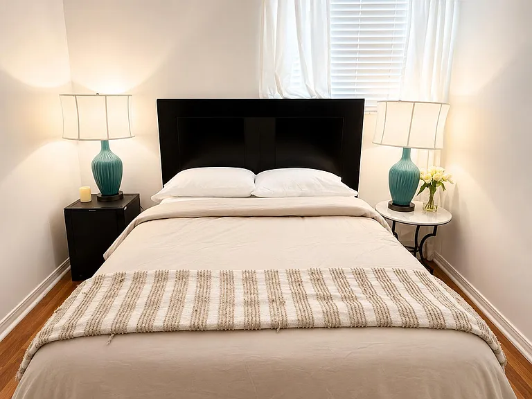 Well-appointed bedroom with a full bed, matching nightstands, and window blinds for light control and privacy.
