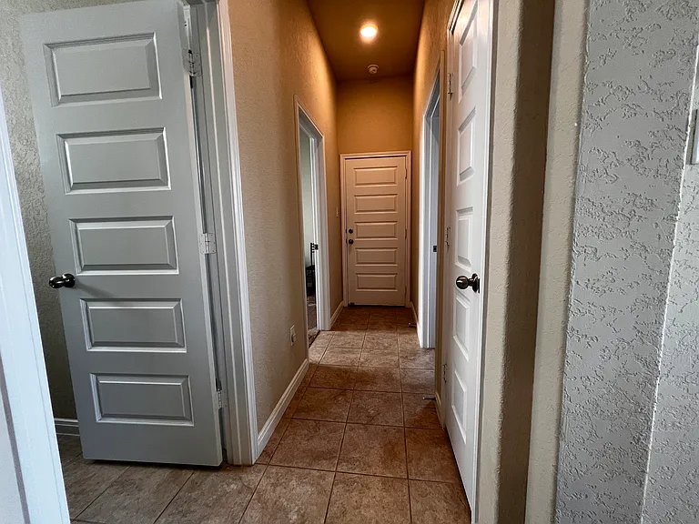 Hallway containing guest bathroom, 2 guests rooms, exit to garage