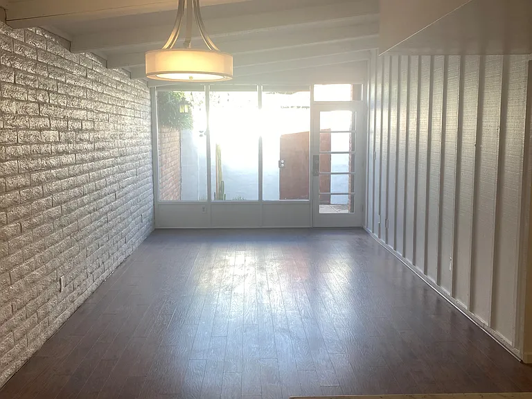 Living/dining with brick and wood walls, plus vaulted beamed ceilings.