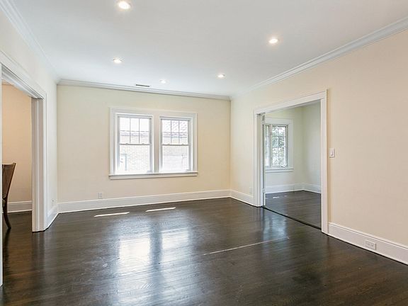 Sun-filled living room with view of entrance to the additional room suitable as den or office. Recessed lights, crown molding.